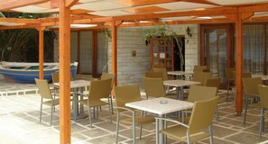Un patio exterior con mesas y sillas, un bote y un muro de piedra.