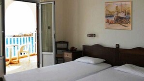 A hotel room with two beds, a desk, a chair, and a painting on the wall. - Maistrali (Serifos)