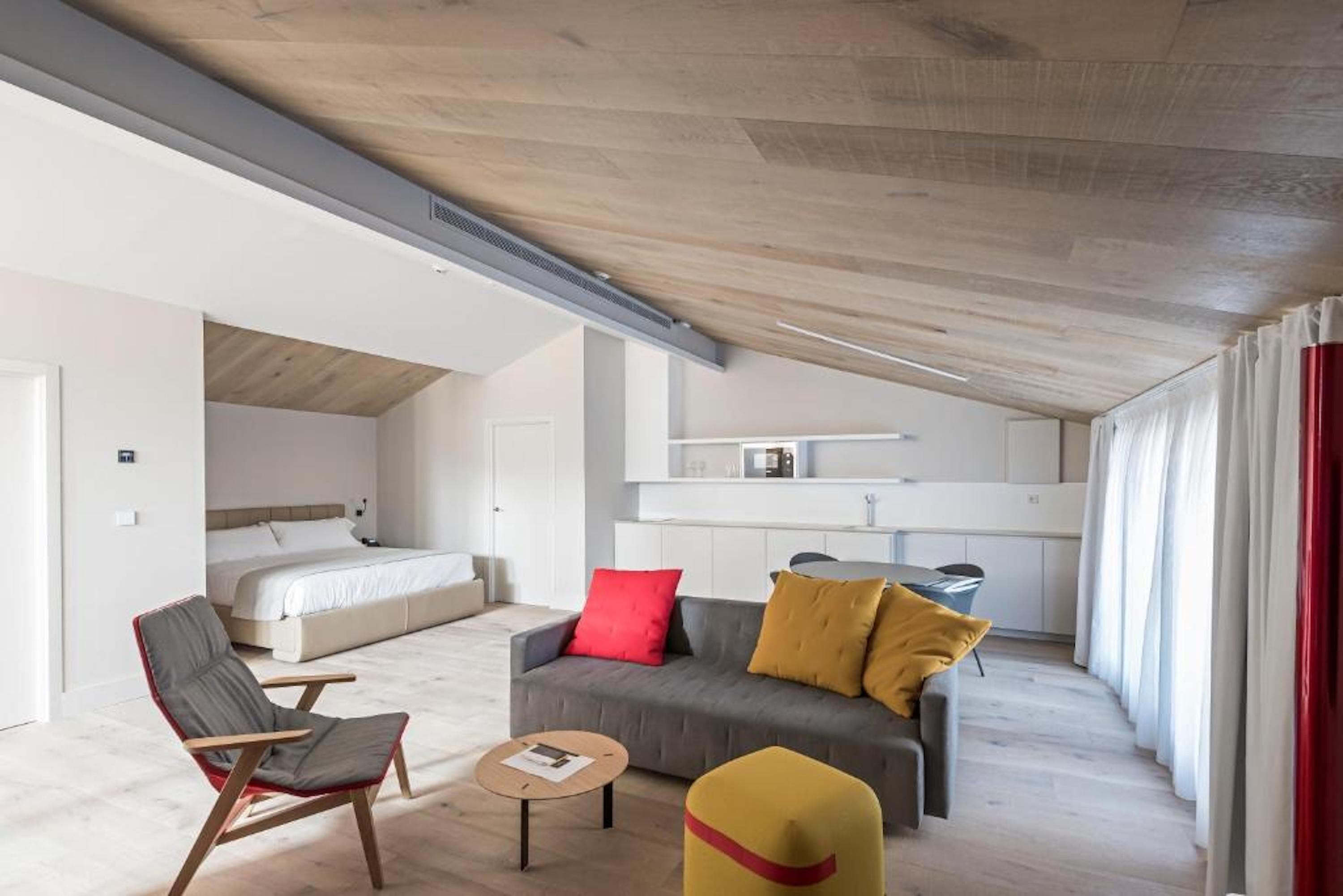 A modern, open-plan living space with a loft bedroom, a dining area, and a kitchen.