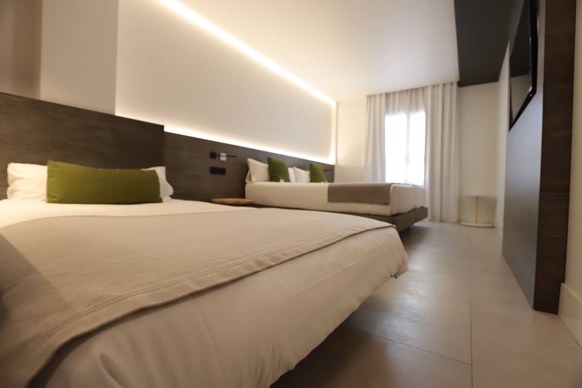 A modern hotel room with a large bed, a bedside table, and a built-in TV.