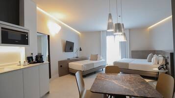 Une chambre d’hôtel moderne et compacte, dotée d’une kitchenette, d’un coin repas, d’un canapé-lit et d’une télévision.