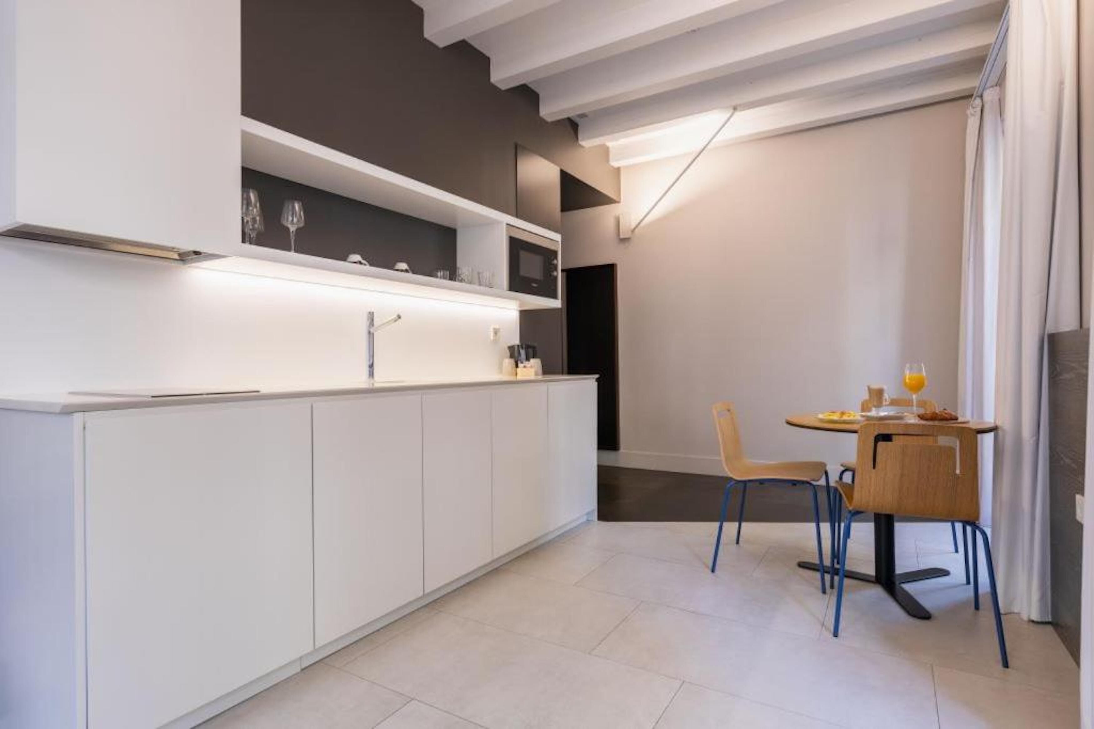 Eine moderne Küche mit weißen Schränken, einer eingebauten Mikrowelle und einem Essbereich mit Tisch und Stühlen.