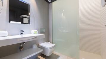 Une salle de bain moderne avec une douche à parois de verre, un lavabo blanc et des toilettes.