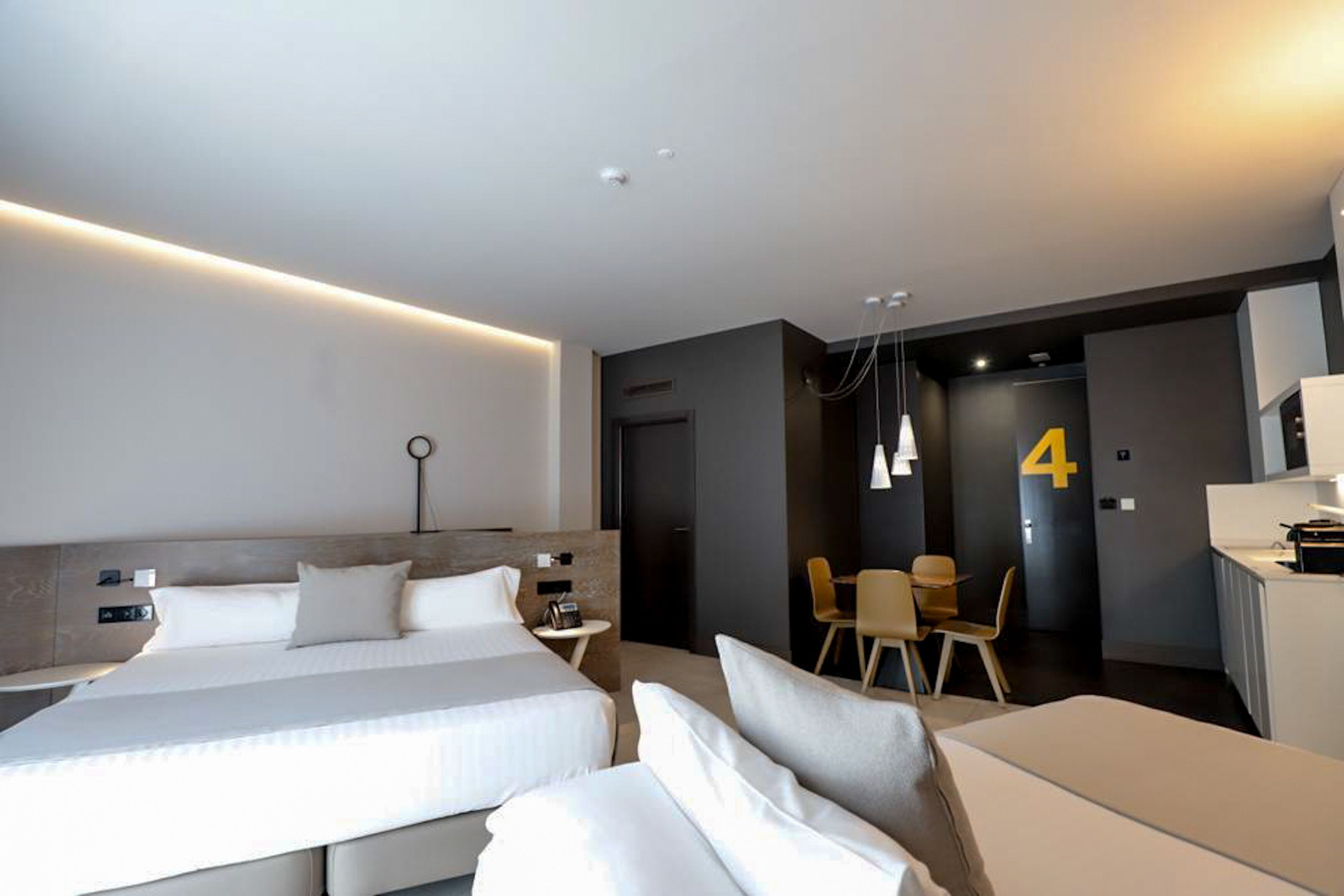 A modern hotel room with a large bed, bedside tables, a desk, and a chair.