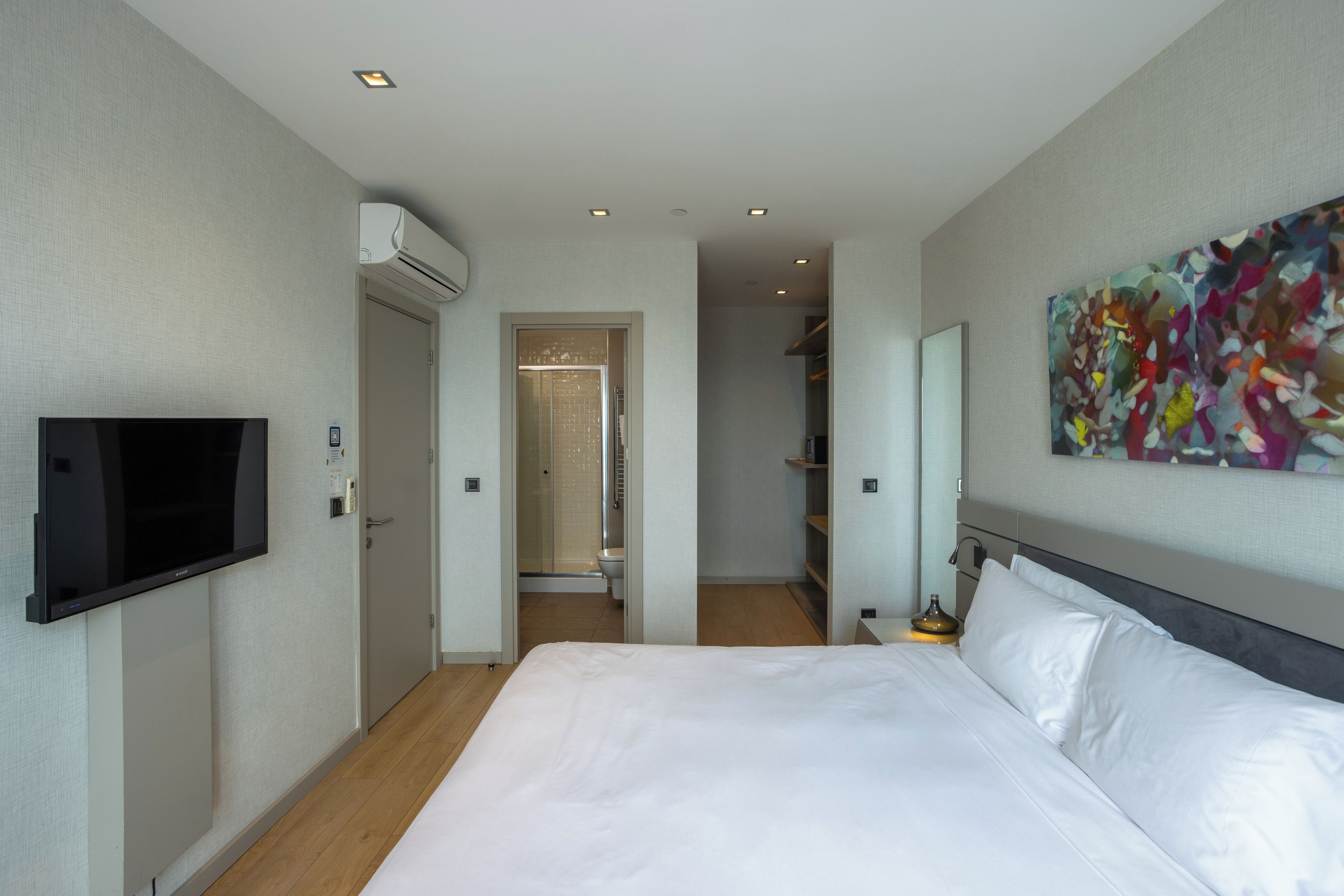 Una habitación de hotel con cama, televisión, ducha y baño.