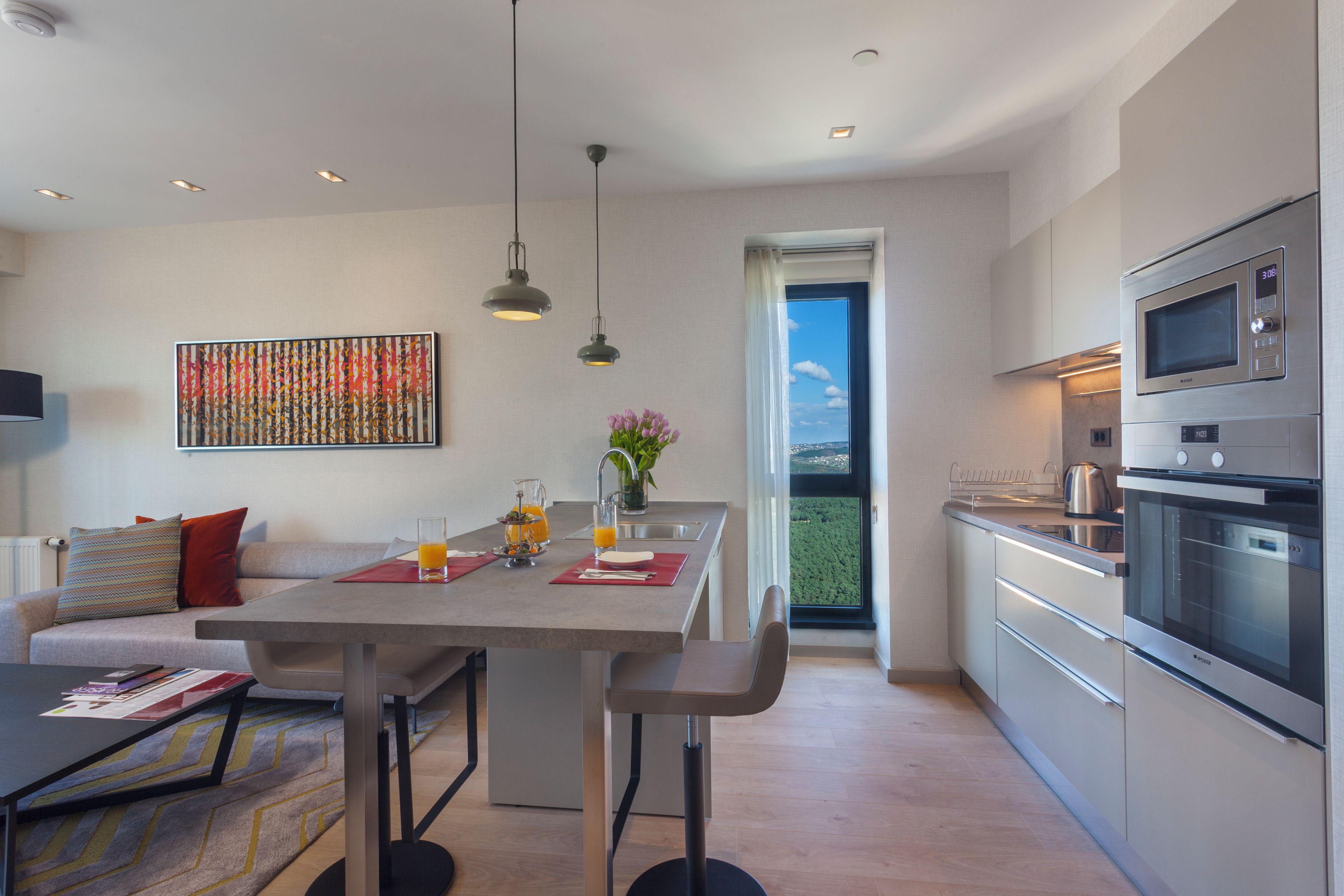 A modern kitchen with a dining area, stainless steel appliances, and a large window.