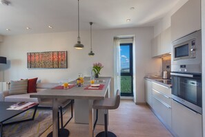 A modern kitchen with a dining area, stainless steel appliances, and a large window. - Antasya Suites (Istanbul)