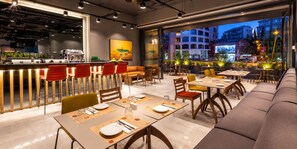 A modern restaurant with a bar area, dining tables, and a view of the cityscape at dusk. - Antasya Suites (Istanbul)