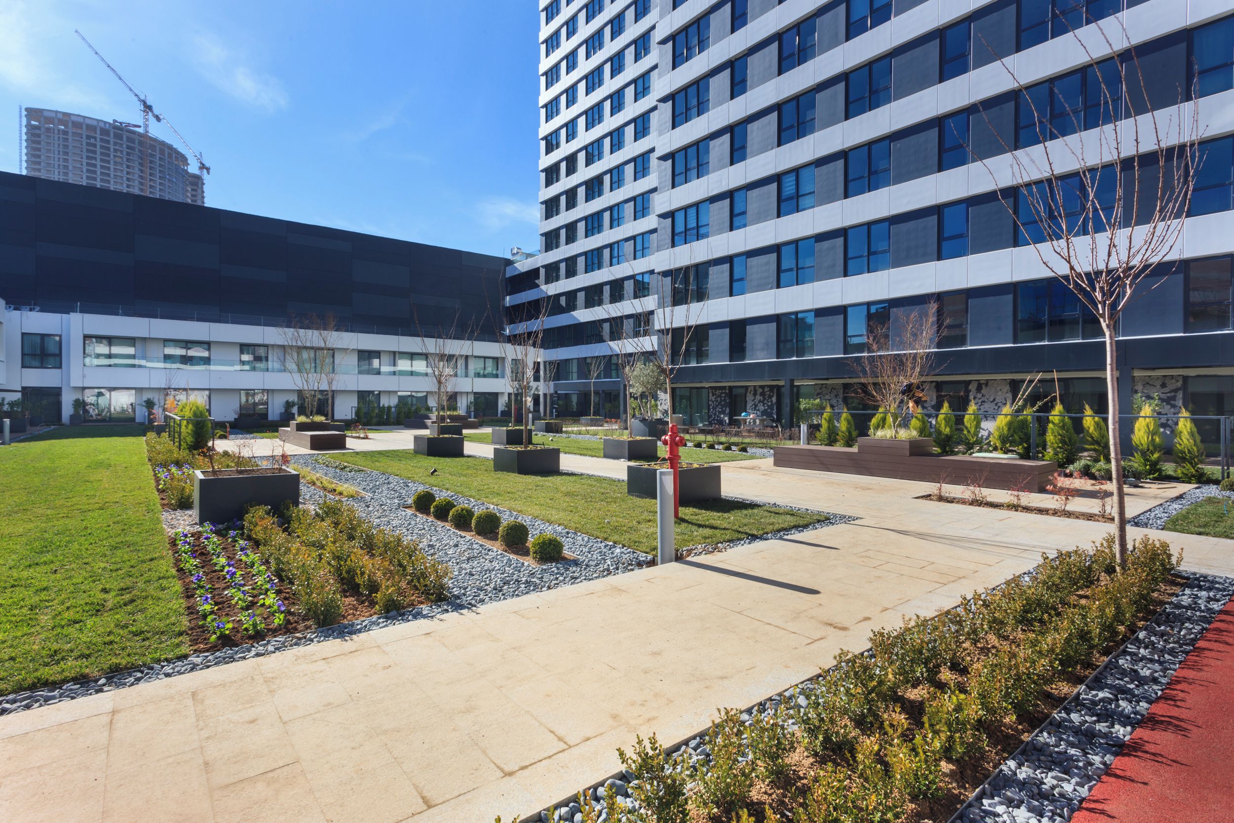 Un bâtiment moderne à plusieurs étages, doté d’une cour intérieure aménagée et surplombant un ciel dégagé.