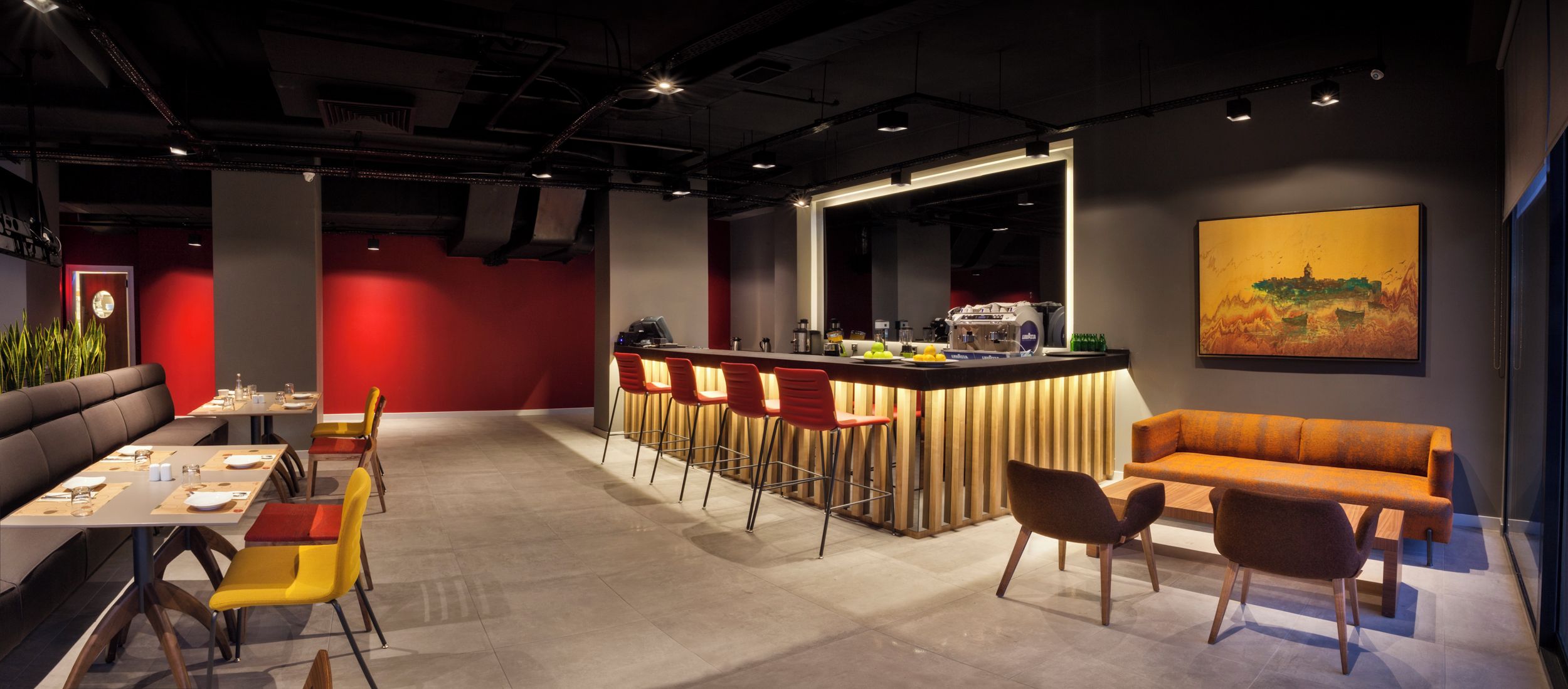 A modern interior with a bar area, seating, and a painting on the wall.