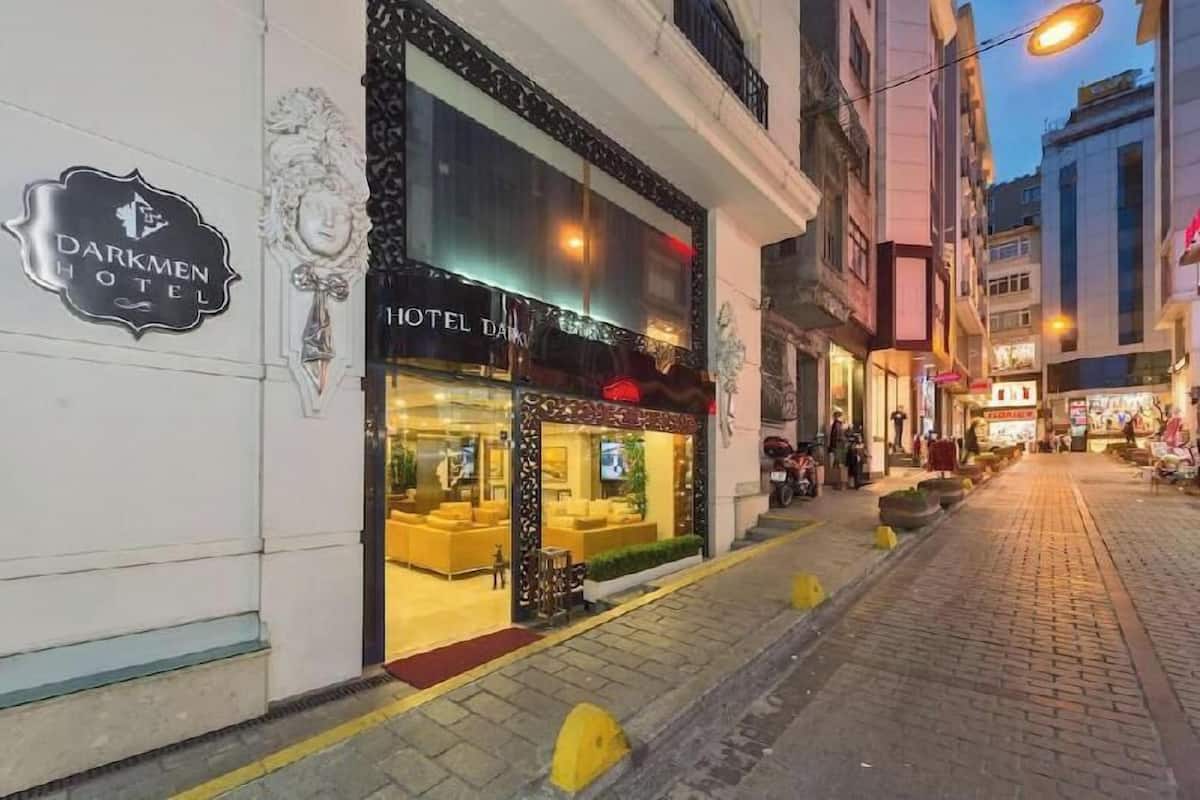 A hotel with a sign reading 'Darkmen Hotel,' a reception area with seating, and a street view with shops.