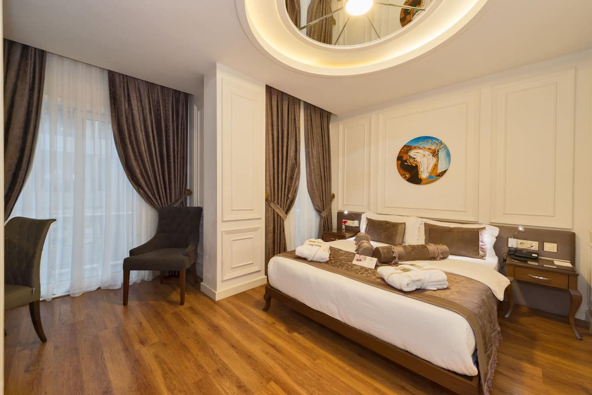 A hotel room with a large bed, a chair, a nightstand, and a round mirror on the ceiling.