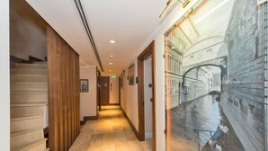 A hotel hallway with a wooden staircase, a tiled floor, and a large mural of a canal scene. - Darkmen 2 Hotel  (Istanbul)