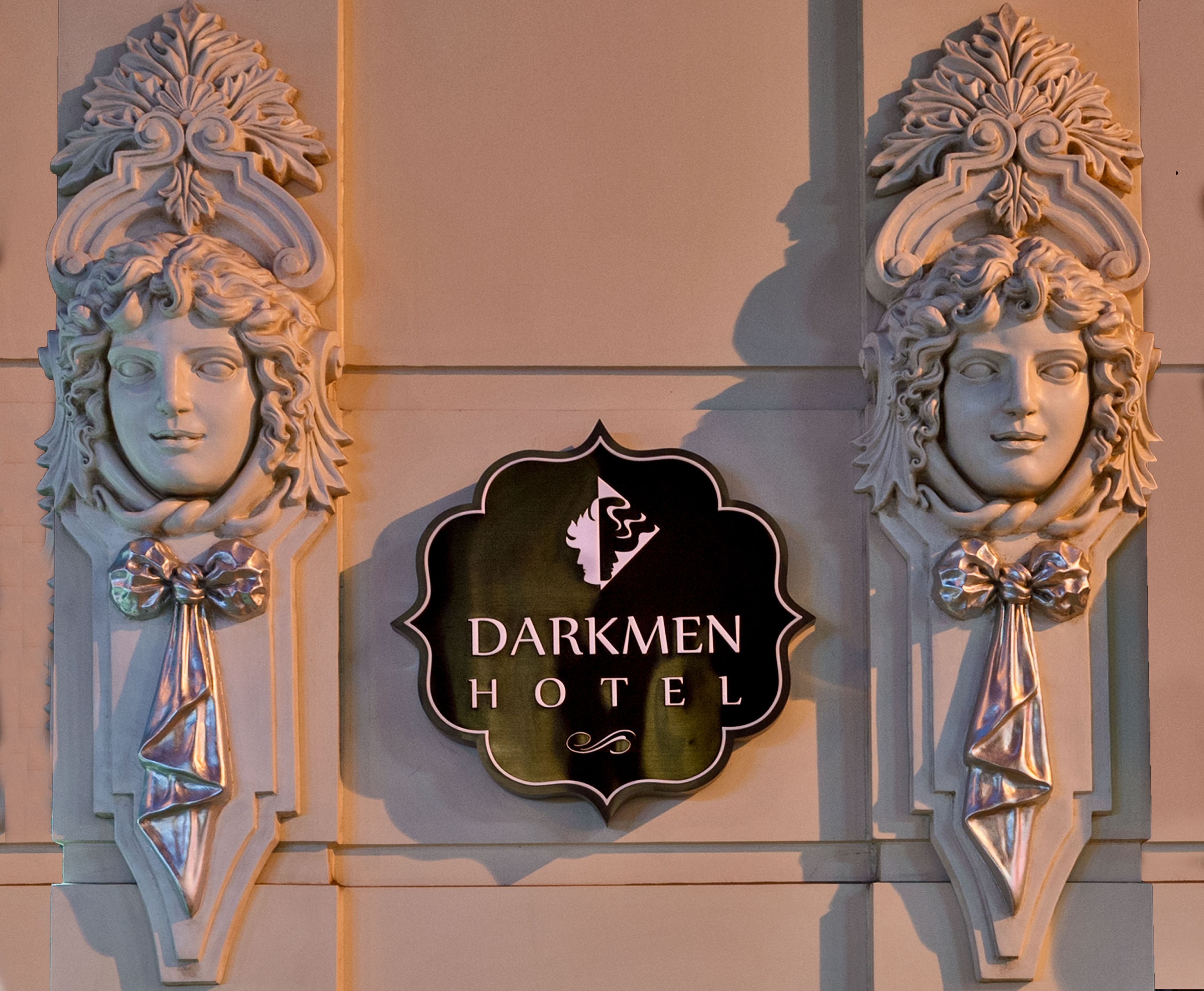 A sign for the Darkmen Hotel with a decorative emblem and two ornate figures.