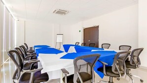 Un salón de conferencias con una larga mesa, varias sillas, una pizarra y una puerta.
