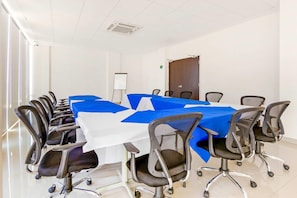 Un salón de conferencias con una larga mesa, varias sillas, una pizarra y una puerta.