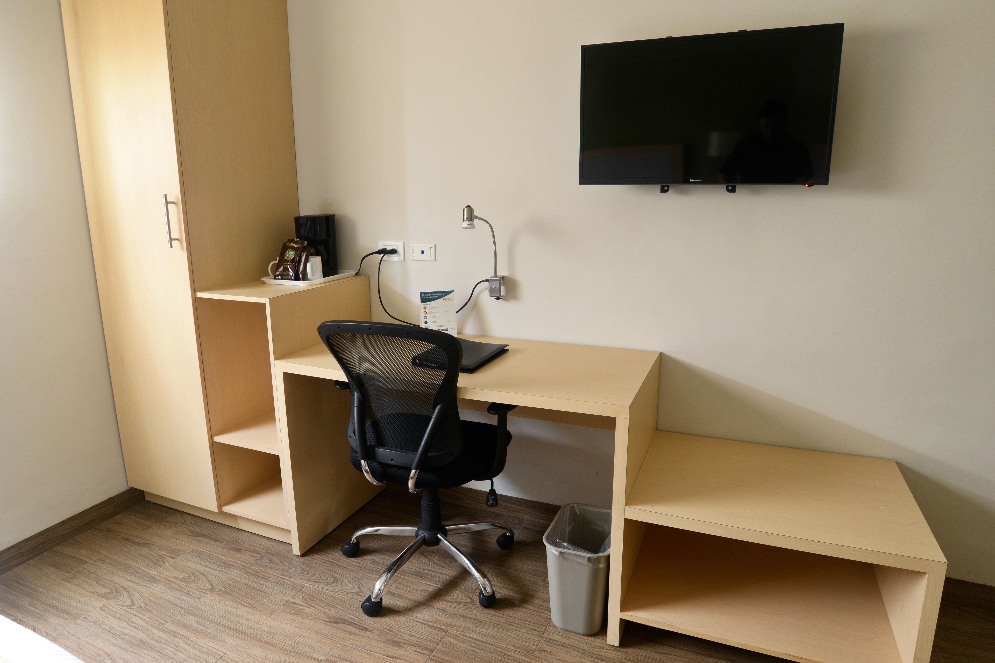Un espace de travail compact comprenant un bureau, une chaise et un téléviseur fixé au mur.