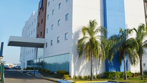 Un hotel Sleep Inn con diseño moderno, que presenta una fachada destacada en azul y blanco, un acceso cubierto y palmeras en primer plano.