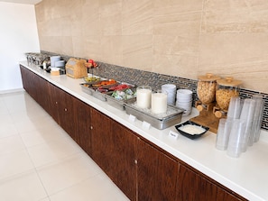 Disposição de buffet com diversos alimentos e recipientes.