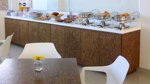 Una cocina moderna con una encimera larga, varios recipientes de comida y un ventanal amplio.