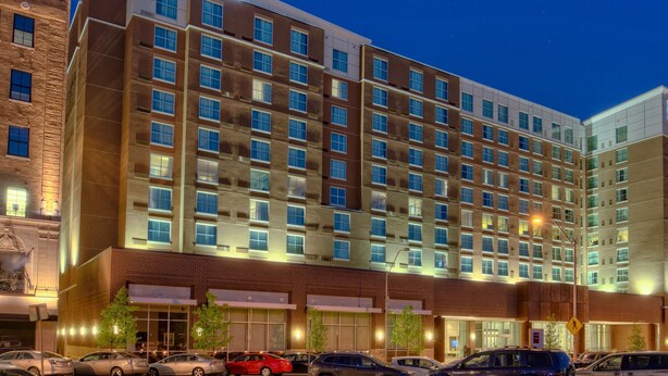 A Courtyard hotel with multiple floors, large windows, and a parking lot with several cars.