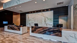 A reception area with marble countertops, a large digital display, and a wooden floor.