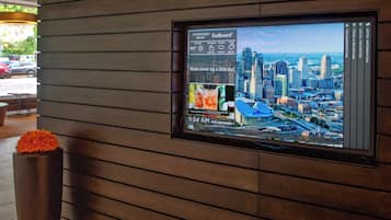 Una pantalla digital muestra un paisaje urbano e información meteorológica.