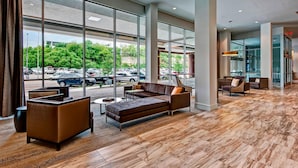 A spacious lobby with large windows, a brown leather sofa, and a coffee table.