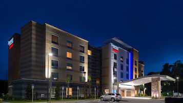 A multi-story hotel with a modern design, featuring a prominent entrance and a parking area.