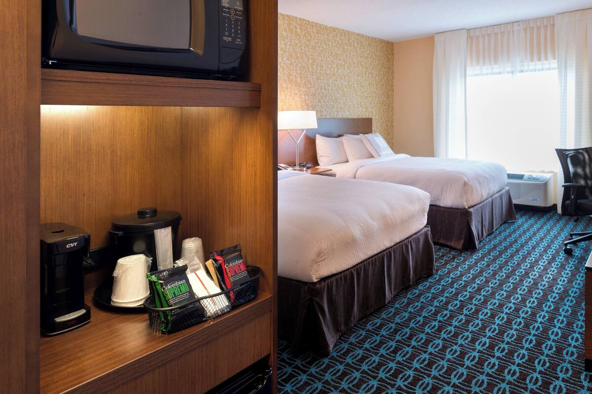Une chambre d’hôtel avec deux lits, une machine à café, un four à micro-ondes et un mini-bar.