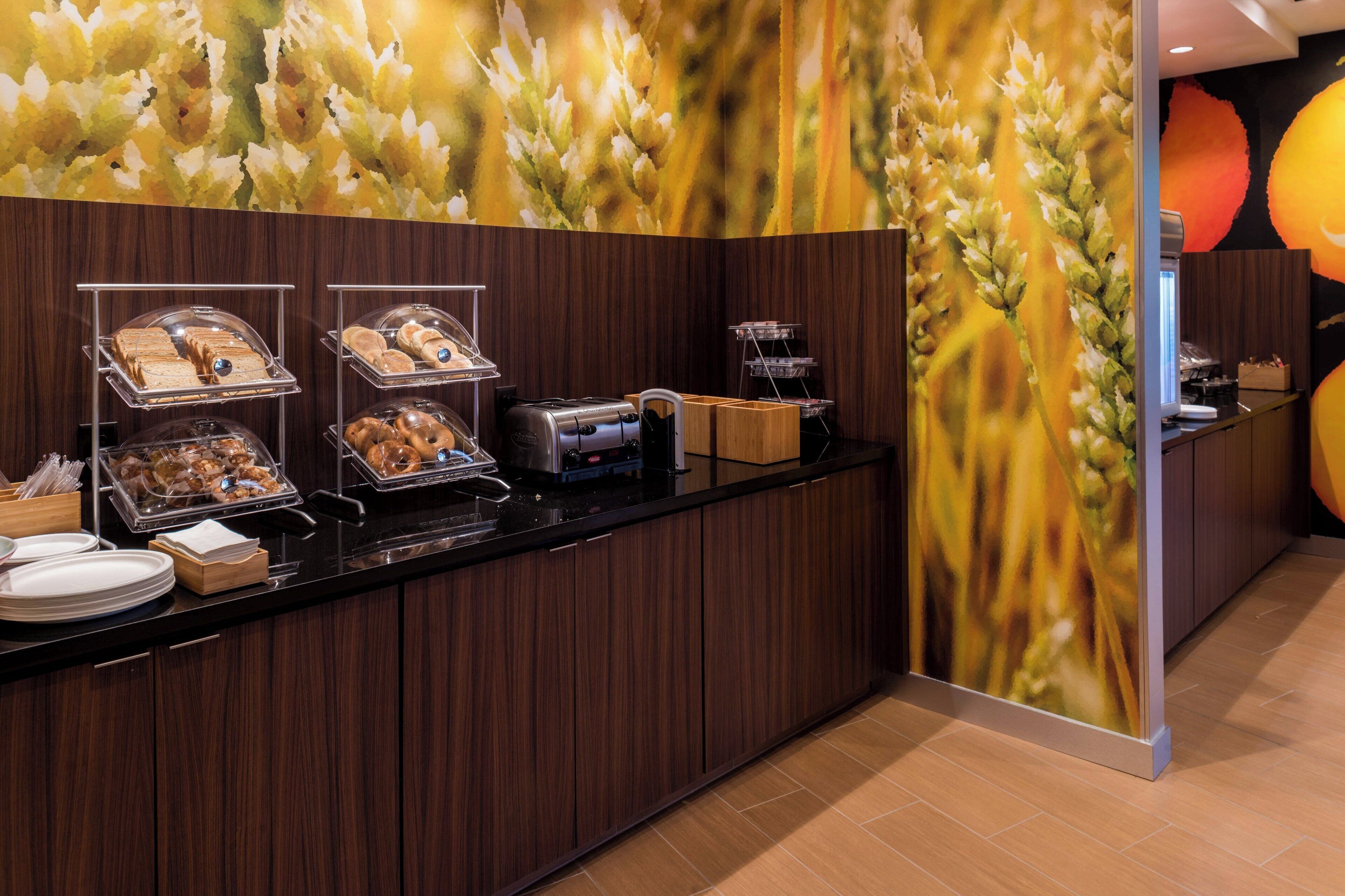 A buffet area with various food items displayed on trays and in containers, a coffee machine, and a wooden counter.