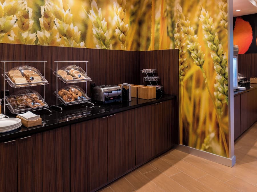 A buffet area with various food items displayed on trays and in containers, a coffee machine, and a wooden counter.
