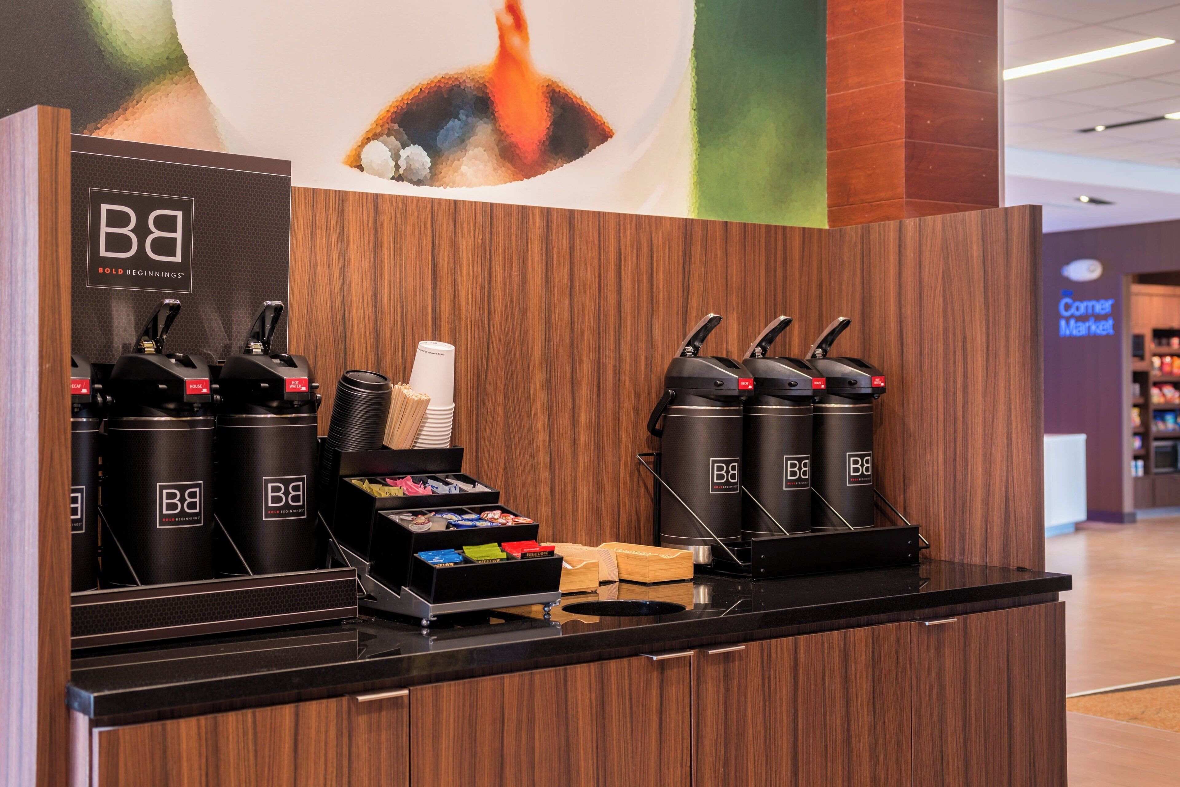 A coffee station with multiple coffee dispensers, a tray with coffee cups, and a display of coffee pods.