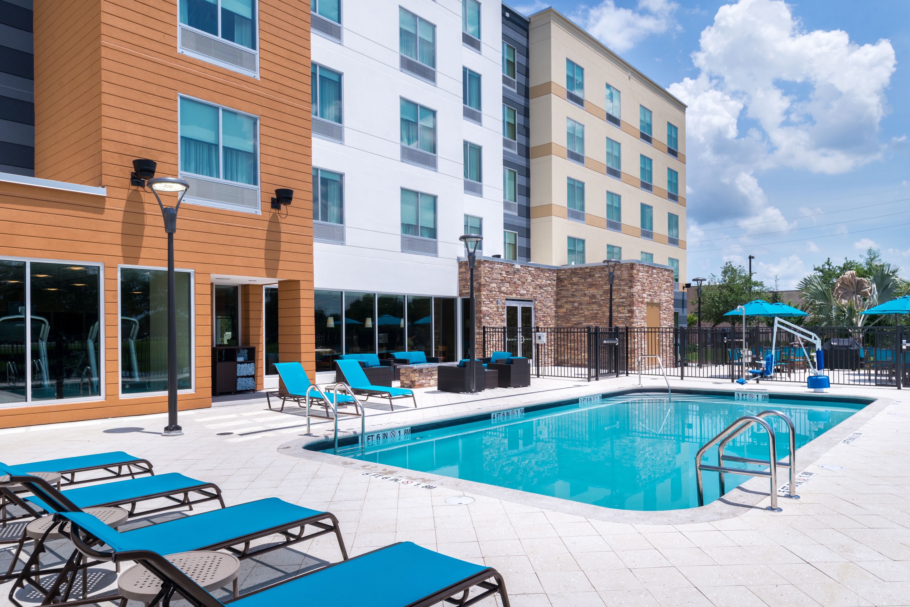 A hotel pool area with lounge chairs, a pool, and a building with multiple floors and windows.