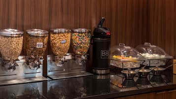 A buffet area with various food dispensers, including cereal, granola, and yogurt.