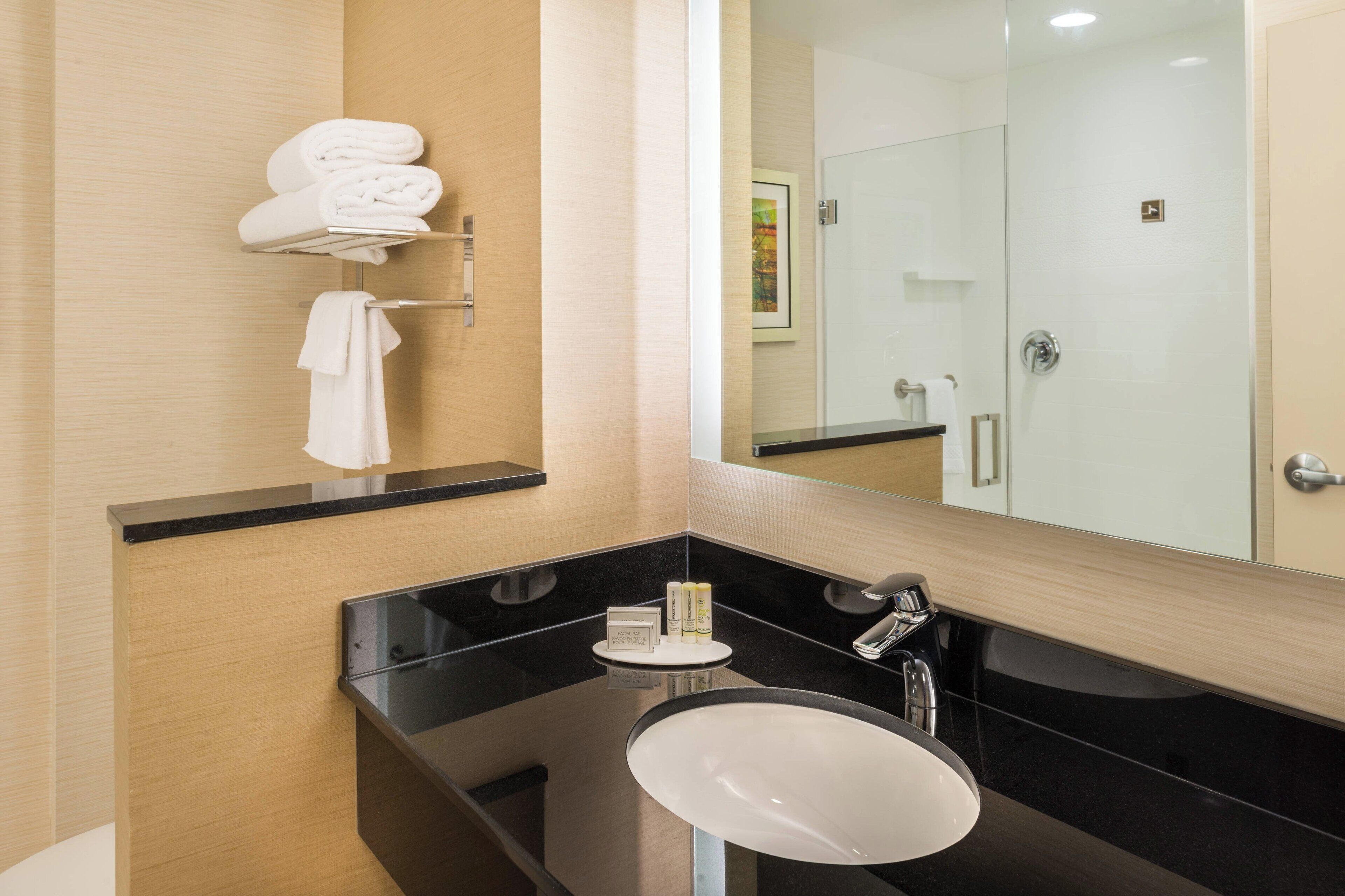A modern bathroom with a black sink, a mirror, and a towel rack.
