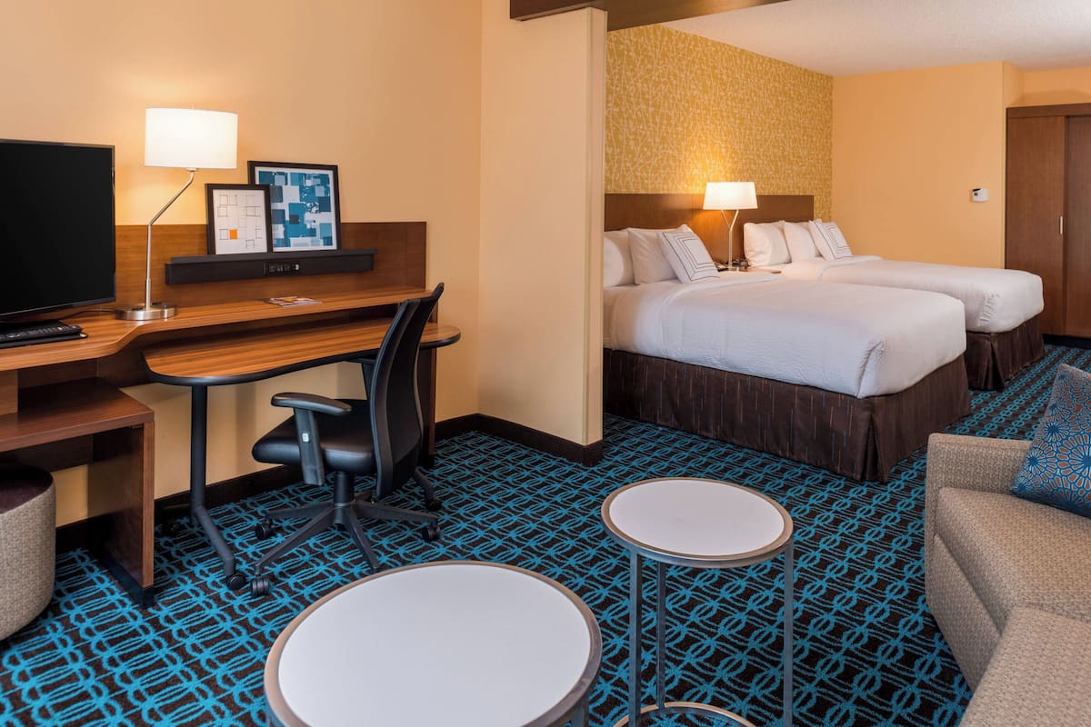 Une chambre d’hôtel équipée d’un bureau, de deux lits, d’une télévision et d’un petit coin salon.