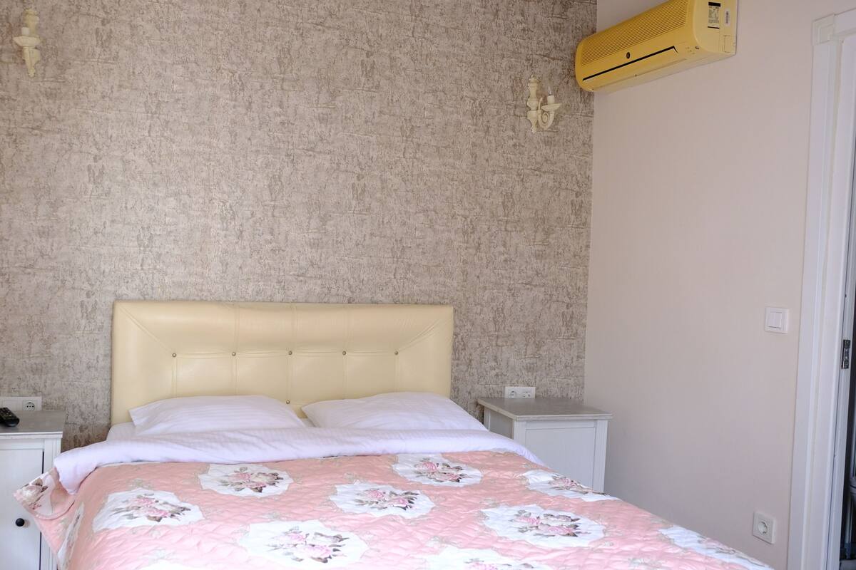 Ein Bett mit einer blumigen Steigedecke, einem Kopfteil und zwei Nachttischen mit Lampen.