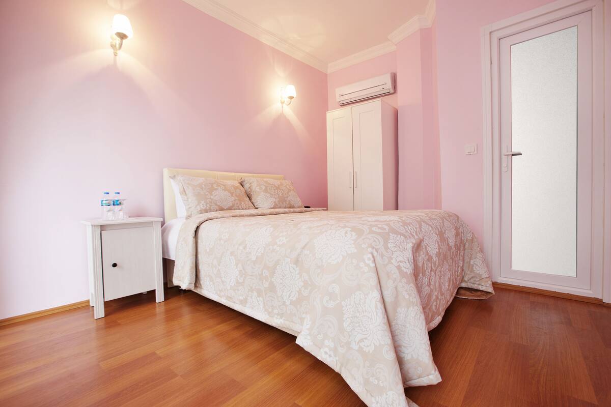 Ein Schlafzimmer mit Bett, Nachttisch, Kleiderschrank und Klimaanlage.