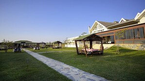 A modern building with a covered outdoor seating area, a stone pathway, and a well-maintained lawn. - Bon Hotel City & Resort (Silivri)