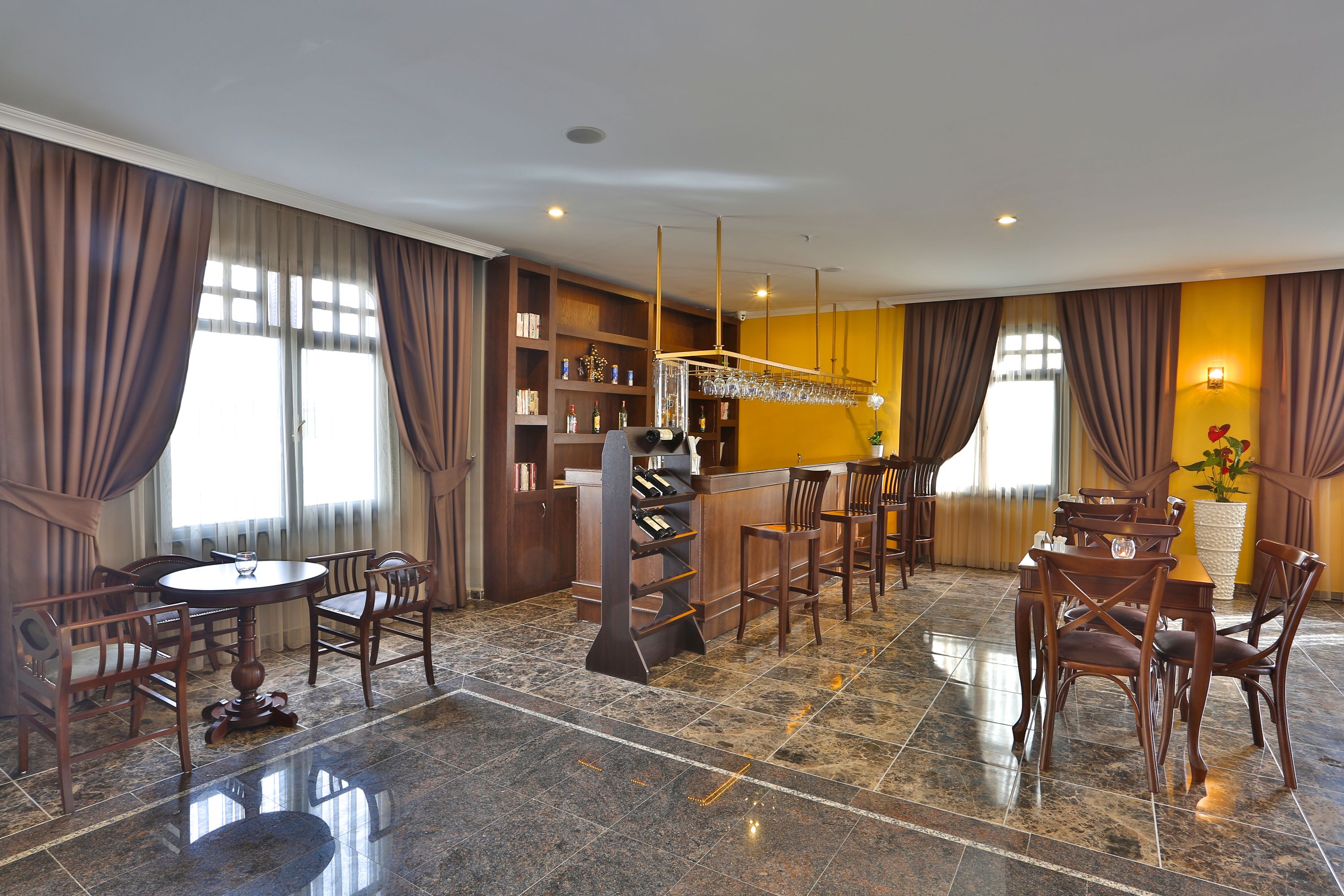 A hotel dining area with a bar, multiple seating arrangements, and a well-lit interior.