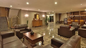A spacious lobby with leather sofas, a wooden coffee table, and a large mirror. - Bon Hotel City & Resort (Silivri)