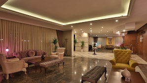 A spacious lobby with a modern sofa set, a yellow armchair, and a reception desk. - Bon Hotel City & Resort (Silivri)