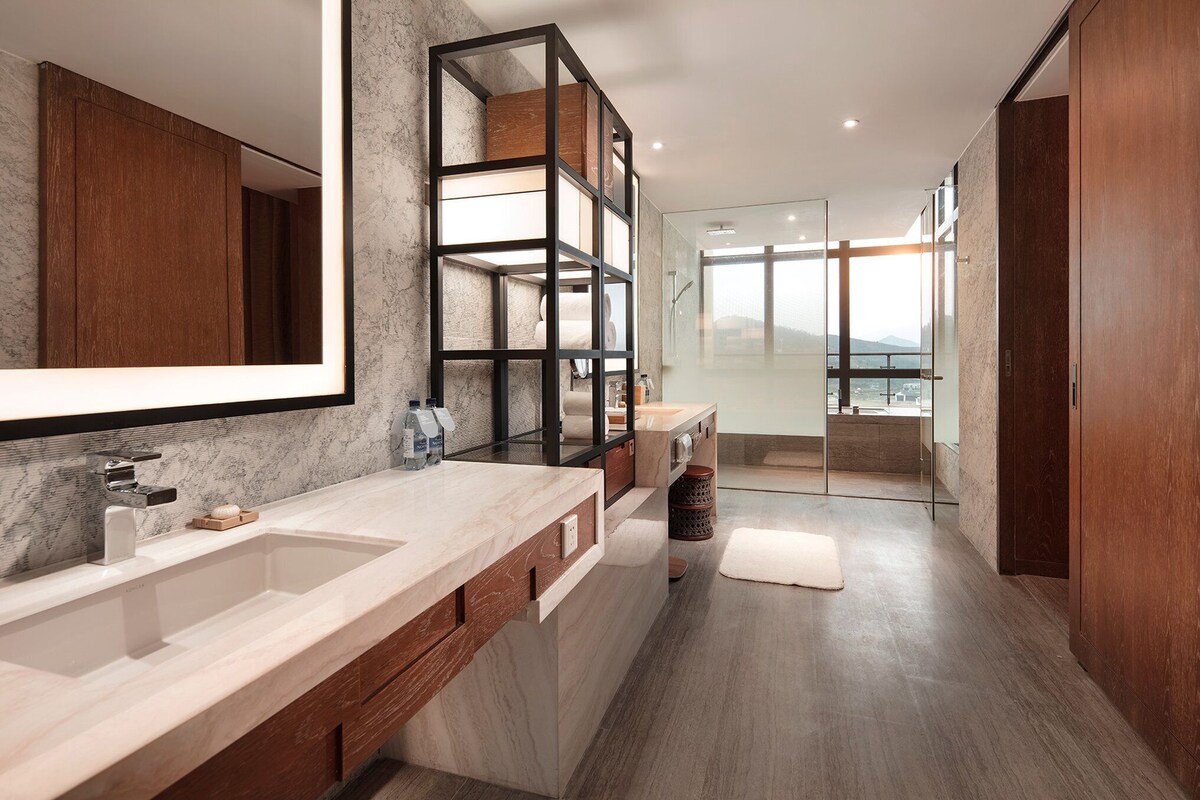 Une salle de bain moderne avec un grand miroir, deux vasques et un espace douche.