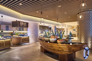 Una cocina moderna con armarios de madera, una isla central con encimera en forma de barco y una variedad de alimentos a la vista.