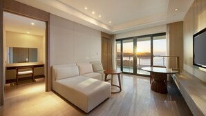 Une chambre d’hôtel moderne dotée d’un grand lit, d’un bureau, d’une table ronde et d’une grande fenêtre donnant sur la mer.