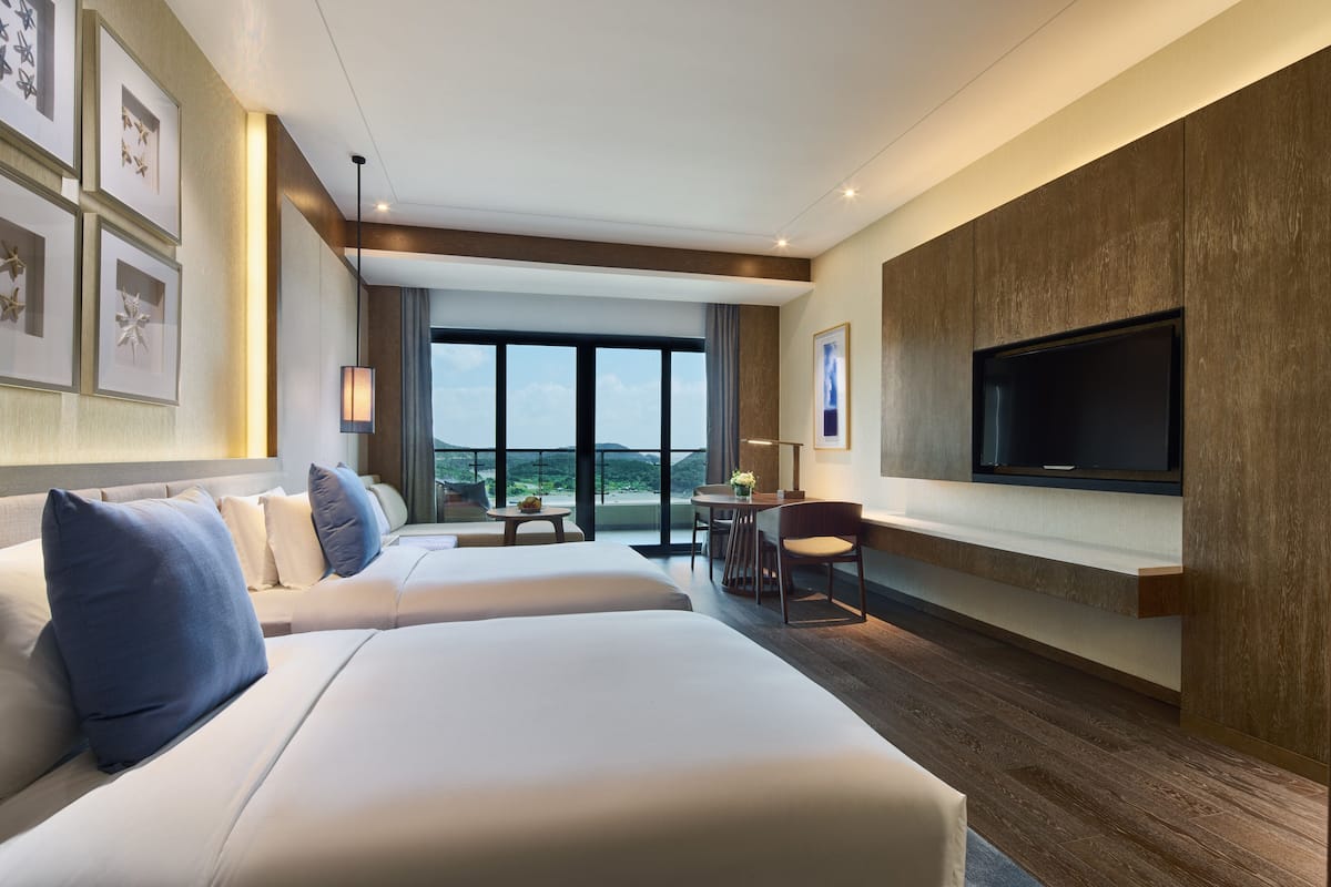 Une chambre d’hôtel moderne dotée d’un grand lit, d’un téléviseur fixé au mur et d’un balcon avec vue.