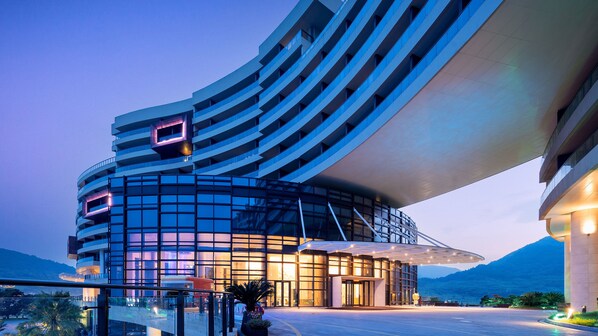 A modern hotel with a curved facade, large glass windows, and a prominent entrance.