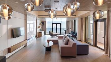 Una sala de estar moderna con un sofá, una mesa de centro y un sillón colgante. Hay un televisor montado en la pared y un ventanal que ofrece vistas al exterior.