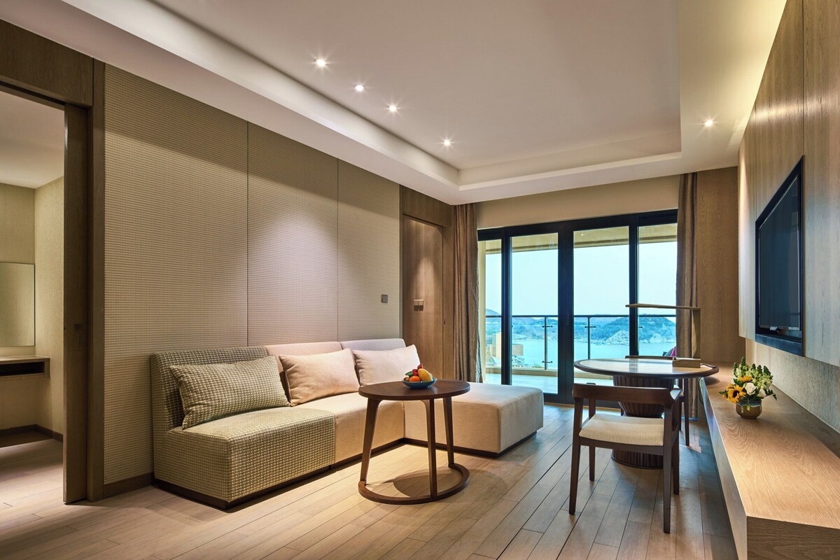 Un salon moderne avec un canapé, une table ronde et une vue sur la mer.